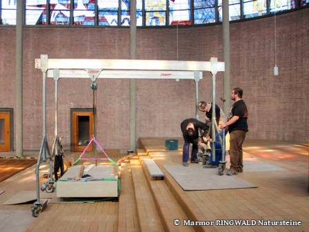 Mit einem Kran wird die Marmorplatte des Altars die Stufen hinau